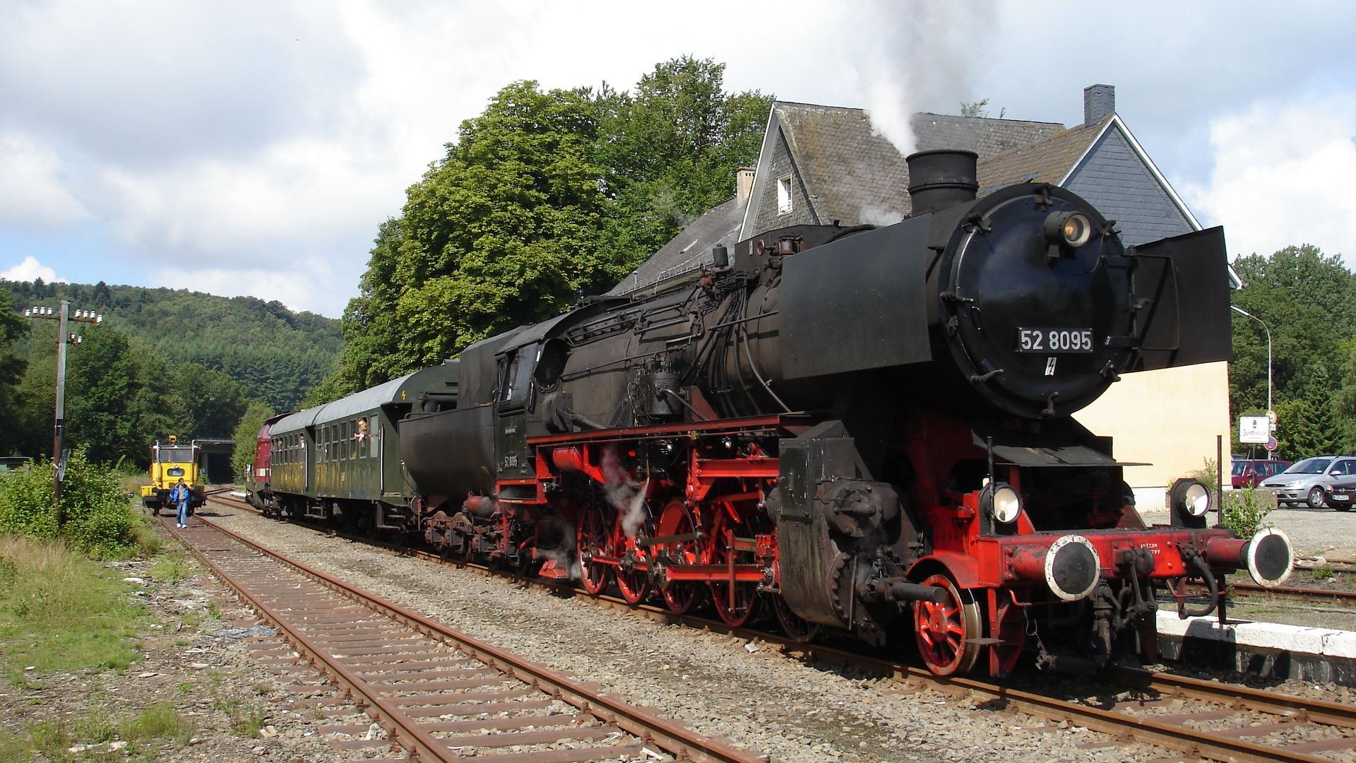 Eine historische Dampflok mit drei Waggons steht auf Schienen im Eisenbahnmuseum.